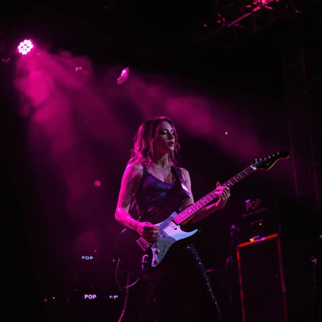 A pop singer on a stage playing guitar